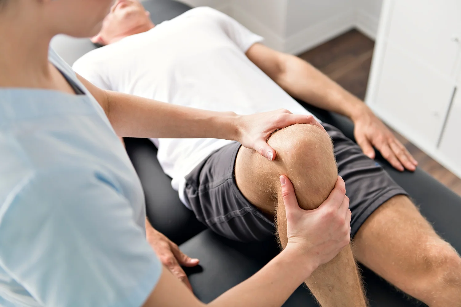 Fizjoterapeuta wykonujący rehabilitację kolana u sportowca po kontuzji.